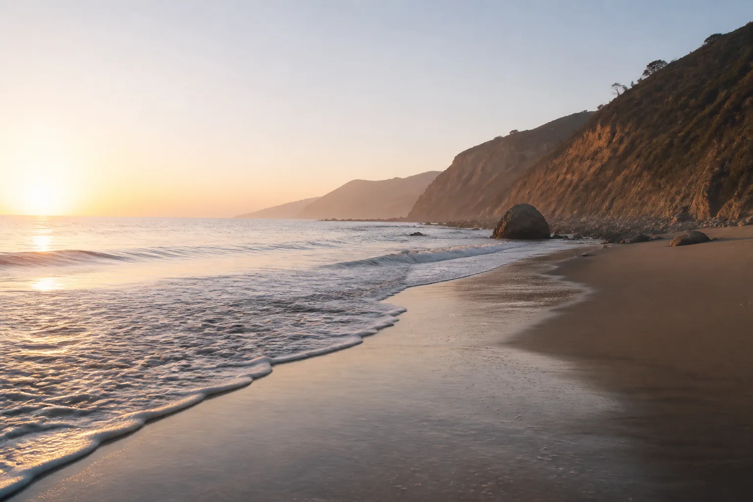A tranquil coastal landscape at dawn with gentle waves and distant cliffs.